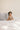 Baby in Earth-toned lougewear set on white bedding by The T-Shirt Bed Co., soft and breathable cotton